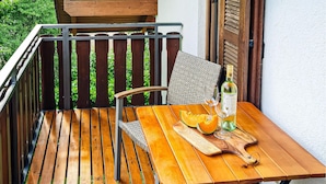 A wooden outdoor table with a chair, a bottle of wine, and a glass on it. - Ferienhaus 16 in Kirchheim (Kirchheim)