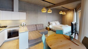 Una habitación de hotel moderna con kitchenette, sofá, cama y comedor.