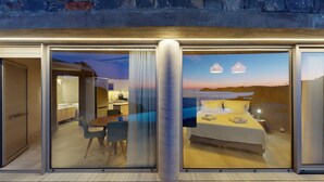Habitación de hotel moderna con pared de vidrio que ofrece vistas al mar al atardecer. En el interior, se puede ver una cama, una pequeña mesa y una zona de estar con vistas a la cocina.