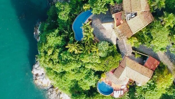 An aerial view of a coastal property with a swimming pool, multiple buildings, and lush greenery. - The Estate at Pacific Vacation | StayPV Luxury Oceanfront with Staff (Zihuatanejo)