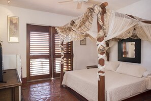Un dormitorio con una cama con dosel, un ventilador de techo y un amplio ventanal con persianas.