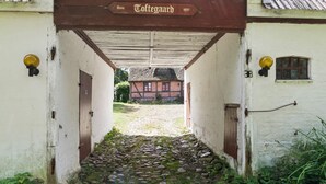 En smal stenlagd gång leder fram till en traditionell byggnad med ett halmtak.