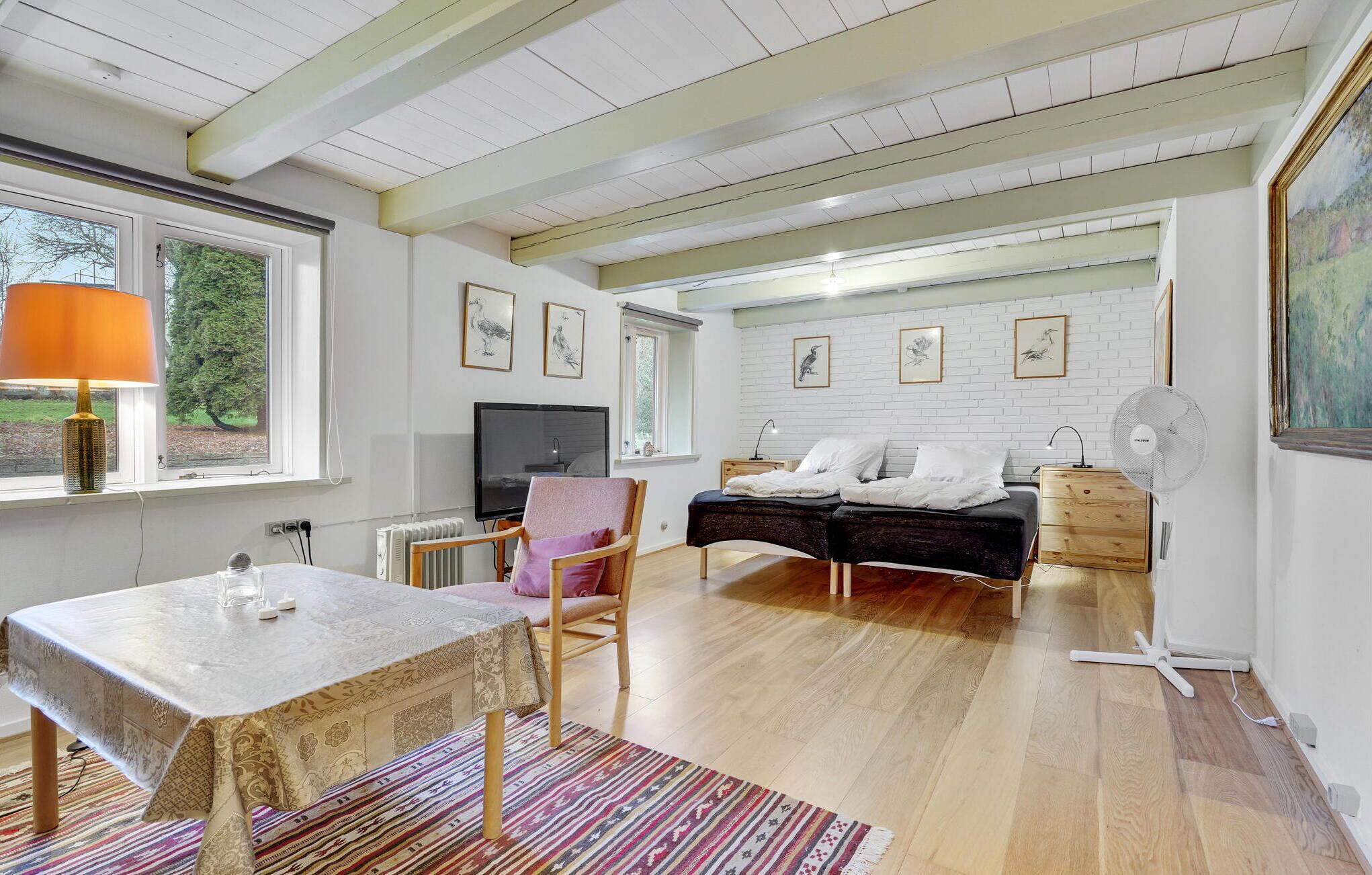 Une chambre moderne avec un lit, une table de chevet et un téléviseur. Il y a également un coin repas avec une table et des chaises.