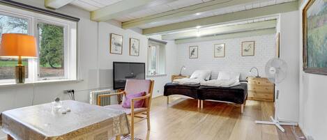 Une chambre moderne avec un lit, une table de chevet et un téléviseur. Il y a également un coin repas avec une table et des chaises.