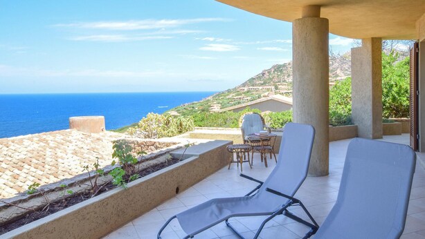 Une terrasse avec vue sur la mer, une table avec des chaises et un fauteuil de relaxation.