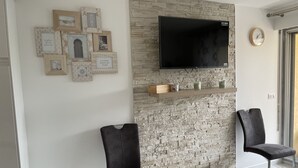 Un salon moderne avec un mur en pierre, un téléviseur fixé au mur et des tableaux encadrés.