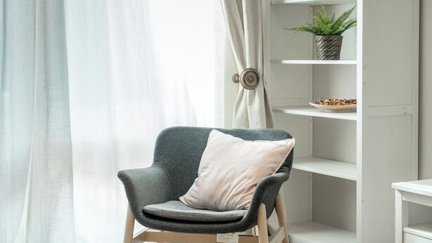 A modern room with a grey armchair, a white shelf with a plant, and a white curtain. - Deluxe 2Bed Duplex w/parking (Greater London)