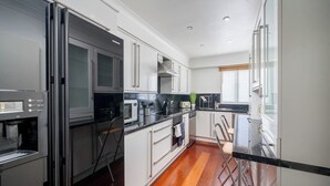 A modern kitchen with white cabinets, a black countertop, and stainless steel appliances. - Deluxe 2Bed Duplex w/parking (Greater London)