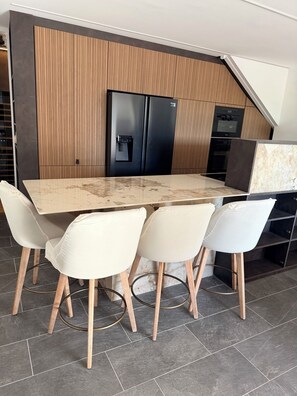 A modern kitchen with a large island, black appliances, and a sloped ceiling.