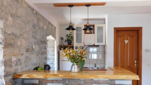 A kitchen with a stone wall, a wooden countertop, a sink, and three bar stools. - Villa Serventi, Apartment with Sea View Balcony (Tivat)