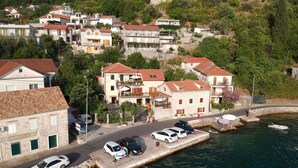 A coastal town with stone buildings, a marina, and parked cars along the waterfront. - Villa Serventi, Apartment with Sea View Balcony (Tivat)