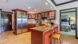 A modern kitchen with wooden cabinets, stainless steel appliances, and a granite countertop. - Waipouli Beach Resort Condo Perfect for Families or Quiet Getaway! (Kapaa)