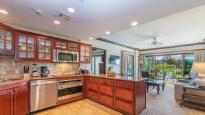 A modern kitchen with stainless steel appliances, wooden cabinets, and a large island. - Waipouli Beach Resort Condo Perfect for Families or Quiet Getaway! (Kapaa)