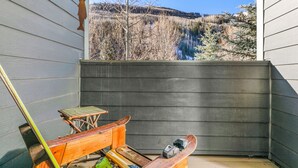 Un balcon donnant sur un lac et une forêt, des meubles en bois et un outil électrique.