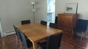 Un coin repas avec une table en bois et des chaises noires, un buffet et un lampadaire.