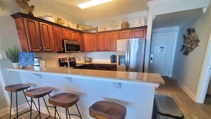 Una cocina moderna con armarios de madera, electrodomésticos de acero inoxidable y una isla central con taburetes de bar.