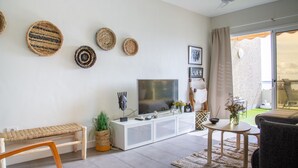 Uma sala de estar moderna com televisão, sofá e área de jantar.
