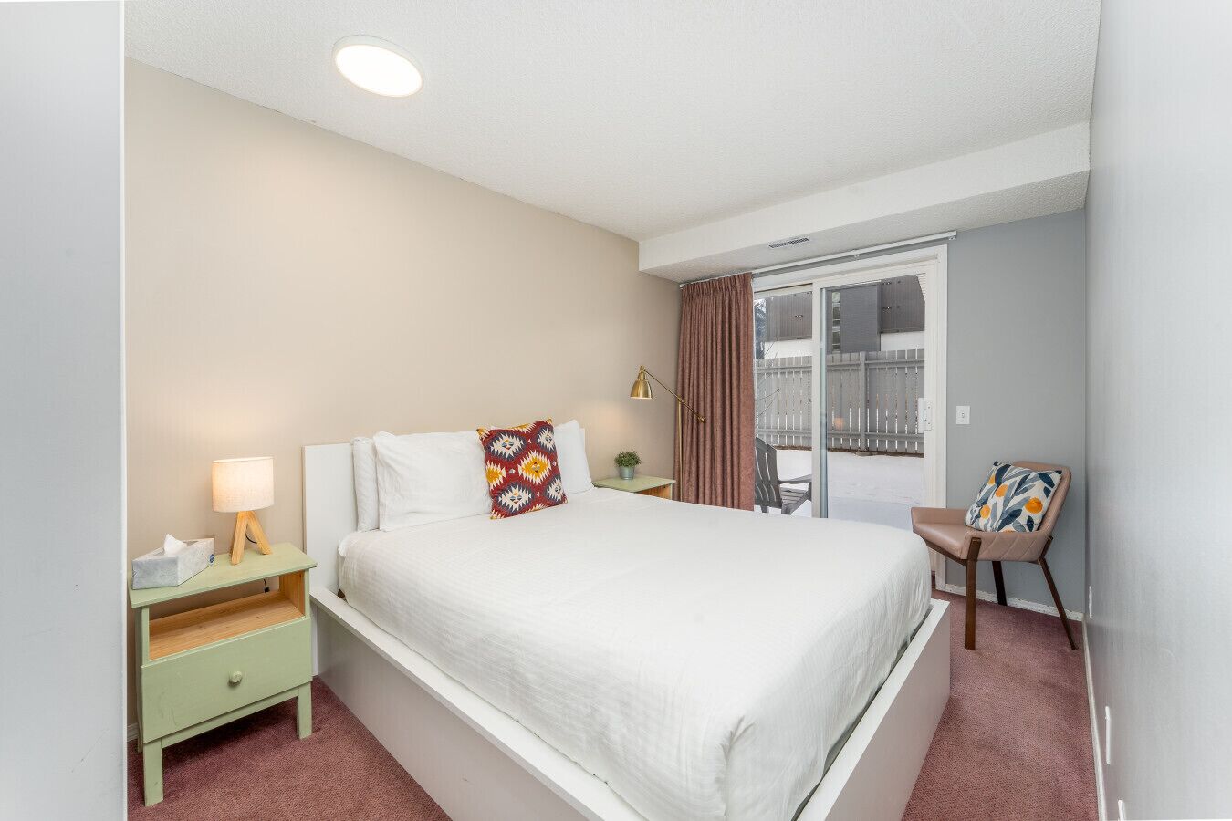 Une chambre d’hôtel avec un lit, une table de chevet, une lampe, une chaise et une vue sur l’extérieur.