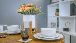 Et spisebord med hvide tallerkener, et glas mørk væske og en vase med blomster.