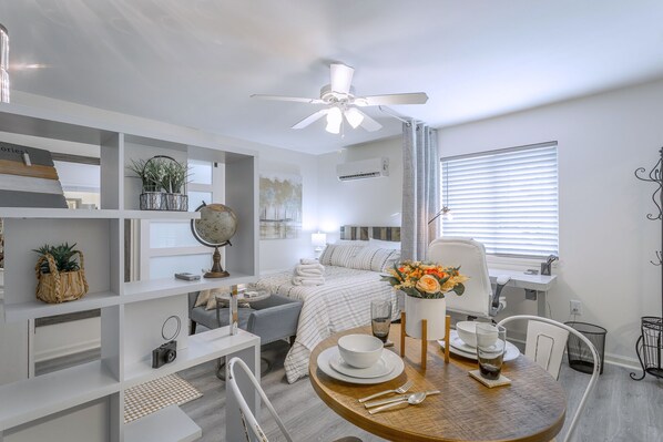 Une chambre moderne et bien éclairée, dotée d’un coin repas, d’un lit avec vue et d’un ventilateur de plafond.