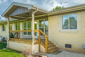 Une maison de plain-pied dotée d’un porche couvert, d’un escalier en bois et d’une façade en briques.