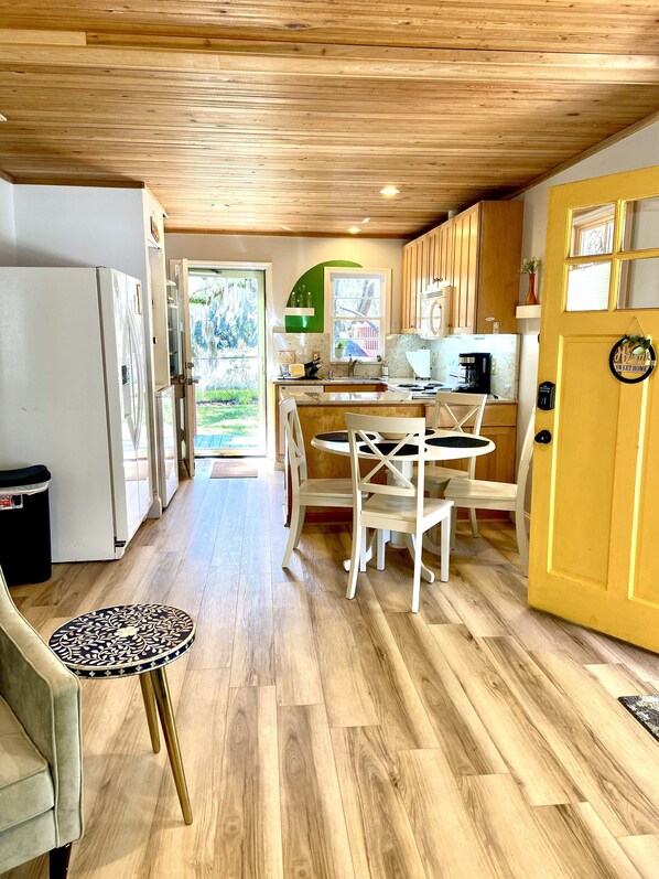 A kitchen with wooden cabinets, a dining area with a table and chairs, and a view of the outdoors.