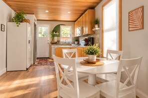 A modern kitchen with white cabinetry, a dining table with chairs, and a potted plant on the table.