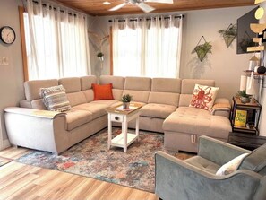 A living room with a sectional sofa, a small side table, a floor lamp, and a rug.