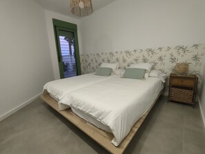 A bedroom with a bed, a nightstand, a door, and a wall with a leaf pattern.
