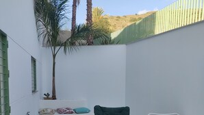 Une terrasse en bois avec une chaise pliante verte et une chaise longue blanche.