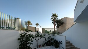 Un espace extérieur moderne agrémenté d’un escalier, de murs blancs et de diverses plantes en pot.