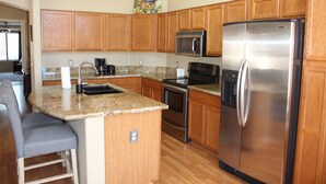 A kitchen with wooden cabinets, a stainless steel refrigerator, a microwave, and a stove. - Private Heated Pool in Apache Junction (Apache Junction)