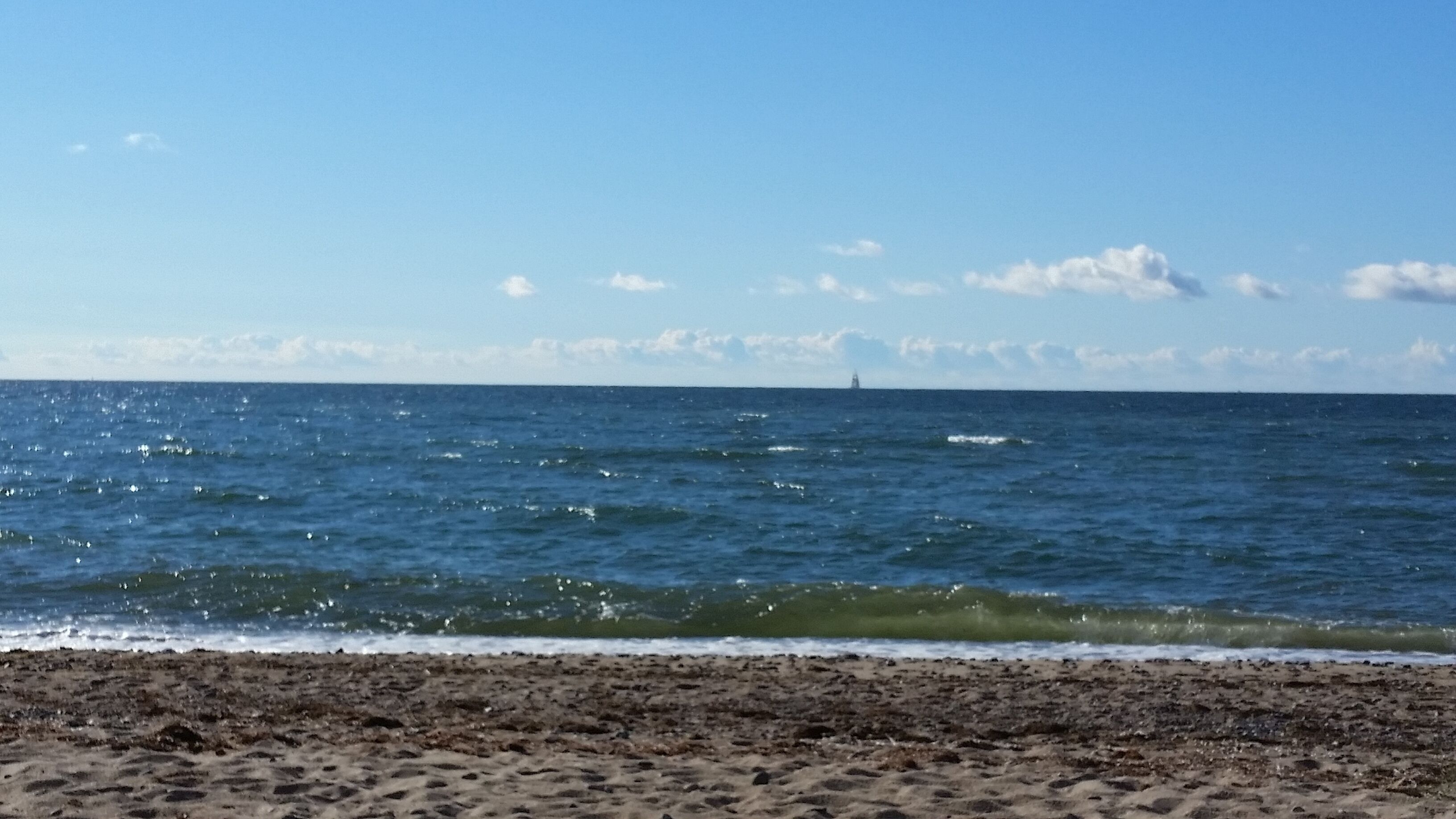 Ein Strand mit sandigem Ufer und dem Meer.