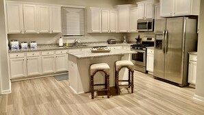 A modern kitchen with white cabinets, a stainless steel refrigerator, a microwave, and a gas stove. - Shimmering Tides~Golf Cart~Secluded (Port St. Joe)