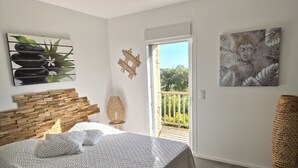 Une chambre à coucher avec un lit, une tête de lit en bois, une grande fenêtre et un balcon.
