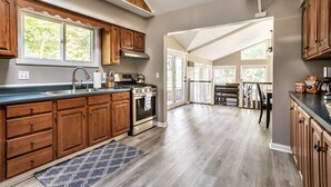 A spacious kitchen with wooden cabinets, a stainless steel sink, and a large window. - Lakeside Cottage w/ Spacious Multi-level Deck and Outdoor Living Space (Monticello)