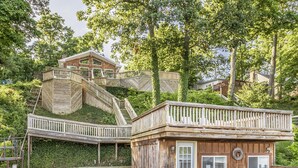 A wooden cabin with a balcony, a staircase, and a door. - Lakeside Cottage w/ Spacious Multi-level Deck and Outdoor Living Space (Monticello)