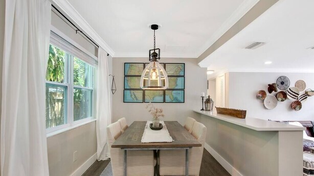 Un comedor con mesa de madera, sillas color beige, una lámpara colgante y un mapa en la pared.