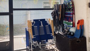A room with a large glass door leading outside, a blue chair with a white cushion, a black storage box, and a colorful bag hanging on the wall.
