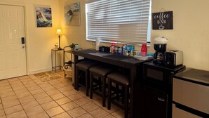 A compact kitchen with a dining area, equipped with a coffee maker, toaster, and a refrigerator.
