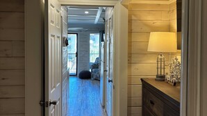 Un pasillo con paredes y techo de madera que conduce a una habitación con cama y ventana.