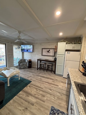 A compact living space with a dining area, kitchen, and a TV mounted on the wall.
