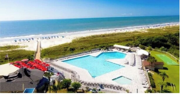 Un resort con una piscina grande, acceso a la playa y vista al océano.