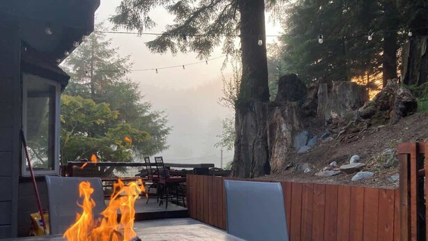 Un patio al aire libre con una chimenea, zona de estar y valla de madera.