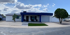 Ein modernes, zweistöckiges Haus mit Garage, einem kleinen Vorgarten mit Rasenmatte und einer Kakteepflanze.