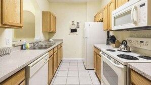 Una cocina con armarios de madera, un refrigerador blanco, una estufa y un microondas.