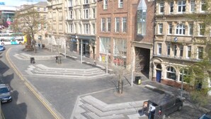 Vista de una calle con edificios históricos, un tranvía y un paso de peatones.