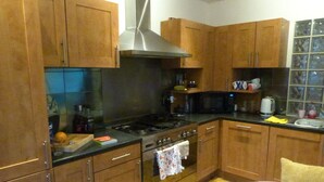 Una cocina con armarios de madera, estufa, horno, microondas y un lavamanos.