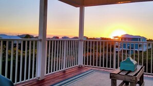 A covered porch with a view of houses and a sunset. - WALK TO PRIVATE ACCESS  "PET FRIENDLY BEACH"  ENJOY 
PRIVATE POOL & HOT TUB (Gulf Shores)