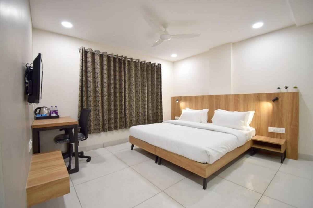 A bedroom with a bed, desk, chair, and a TV.